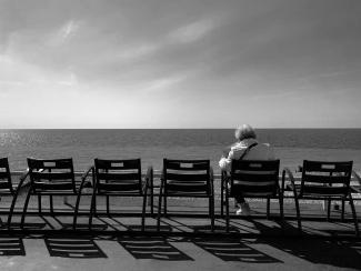 a person sitting on a bench looking out at the ocean by Paolo Chiabrando courtesy of Unsplash.