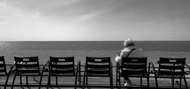 a person sitting on a bench looking out at the ocean by Paolo Chiabrando courtesy of Unsplash.